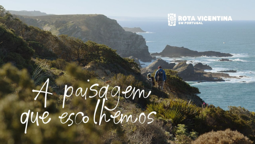 Paisagem costeira em dia de sol com pessoas a caminhar